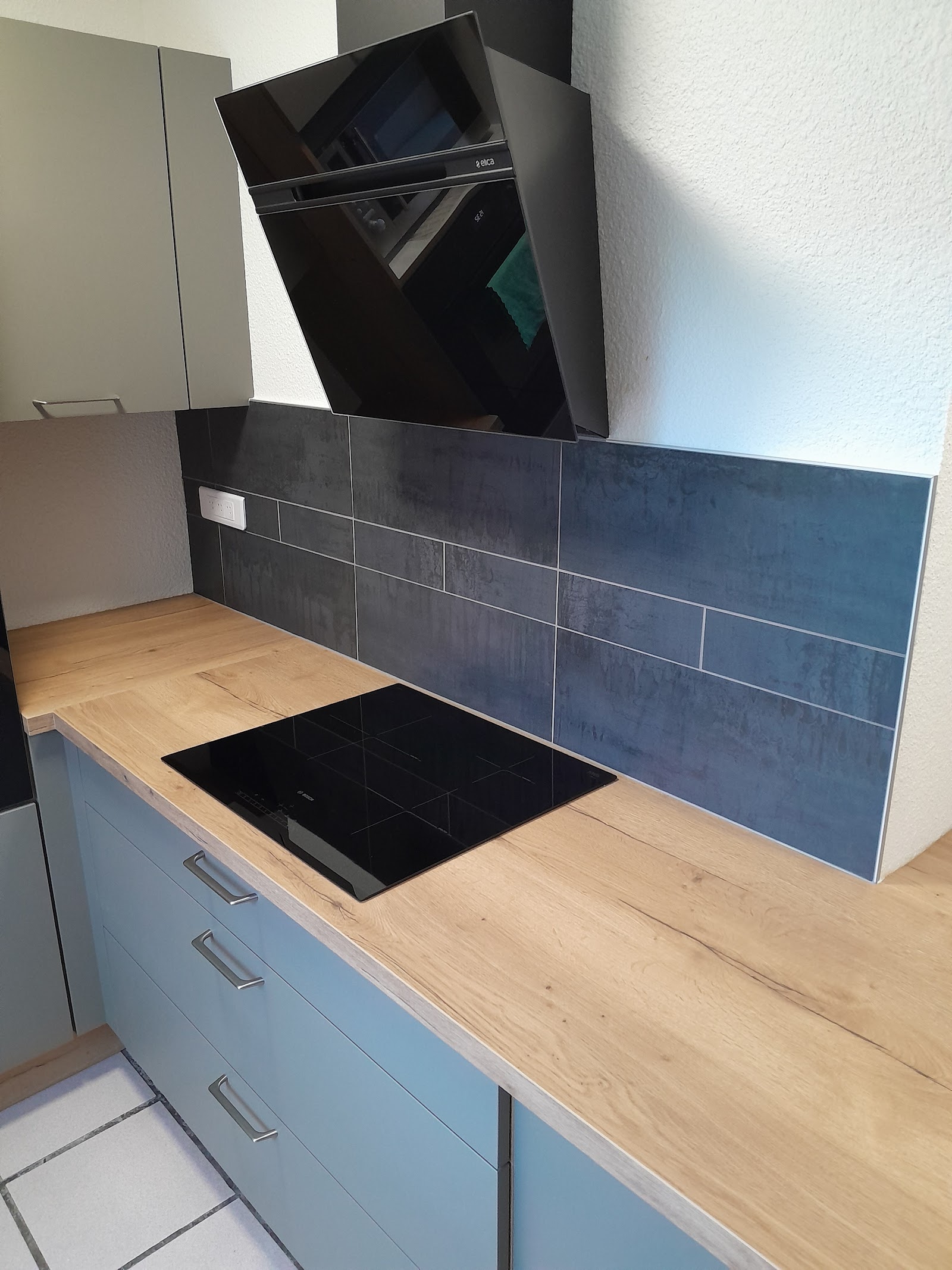 Crédence de cuisine en carreaux gris anthracite sur plan de travail en chêne.