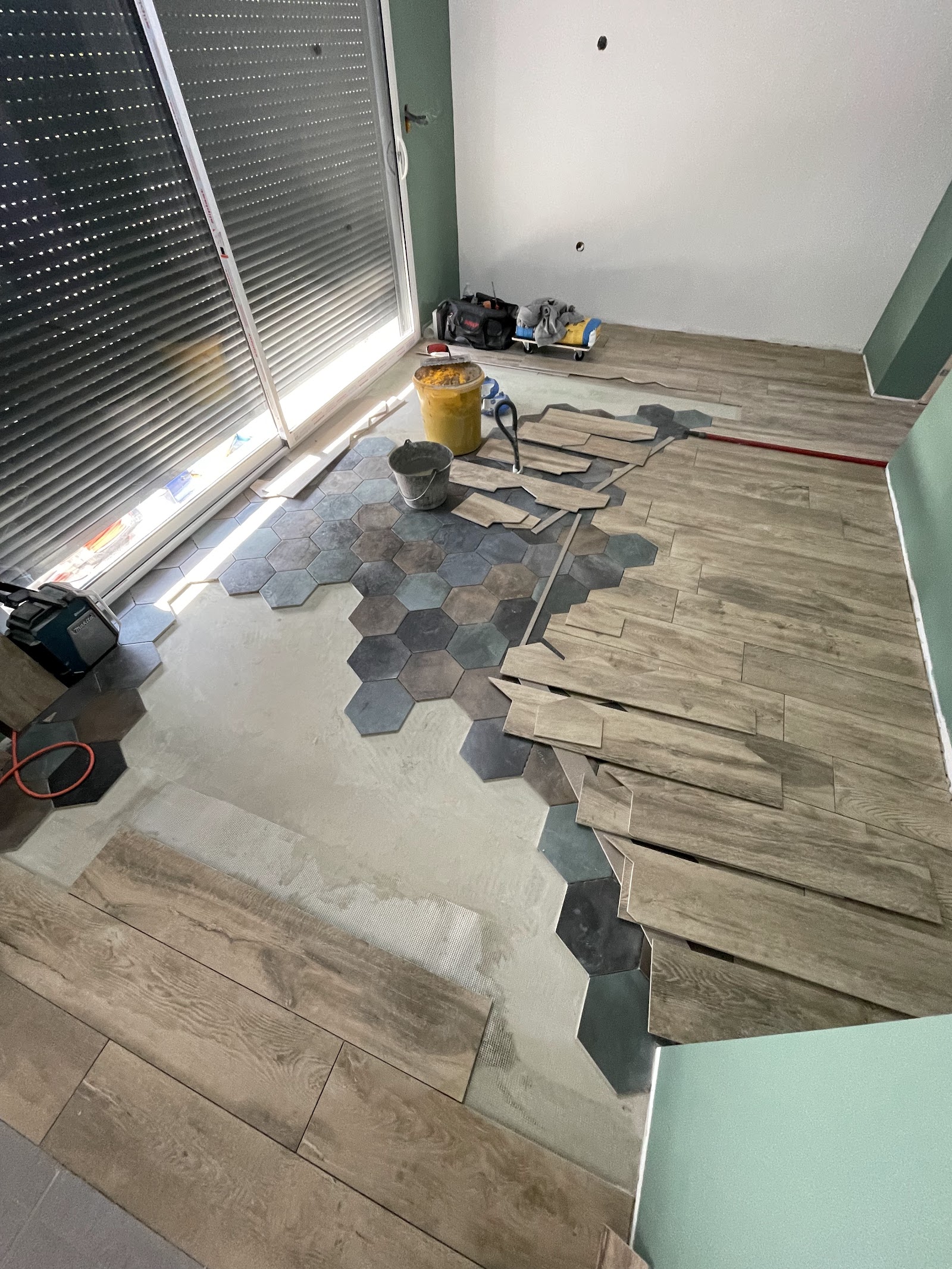 Transition décorative entre un carrelage hexagonal et un sol effet parquet.
