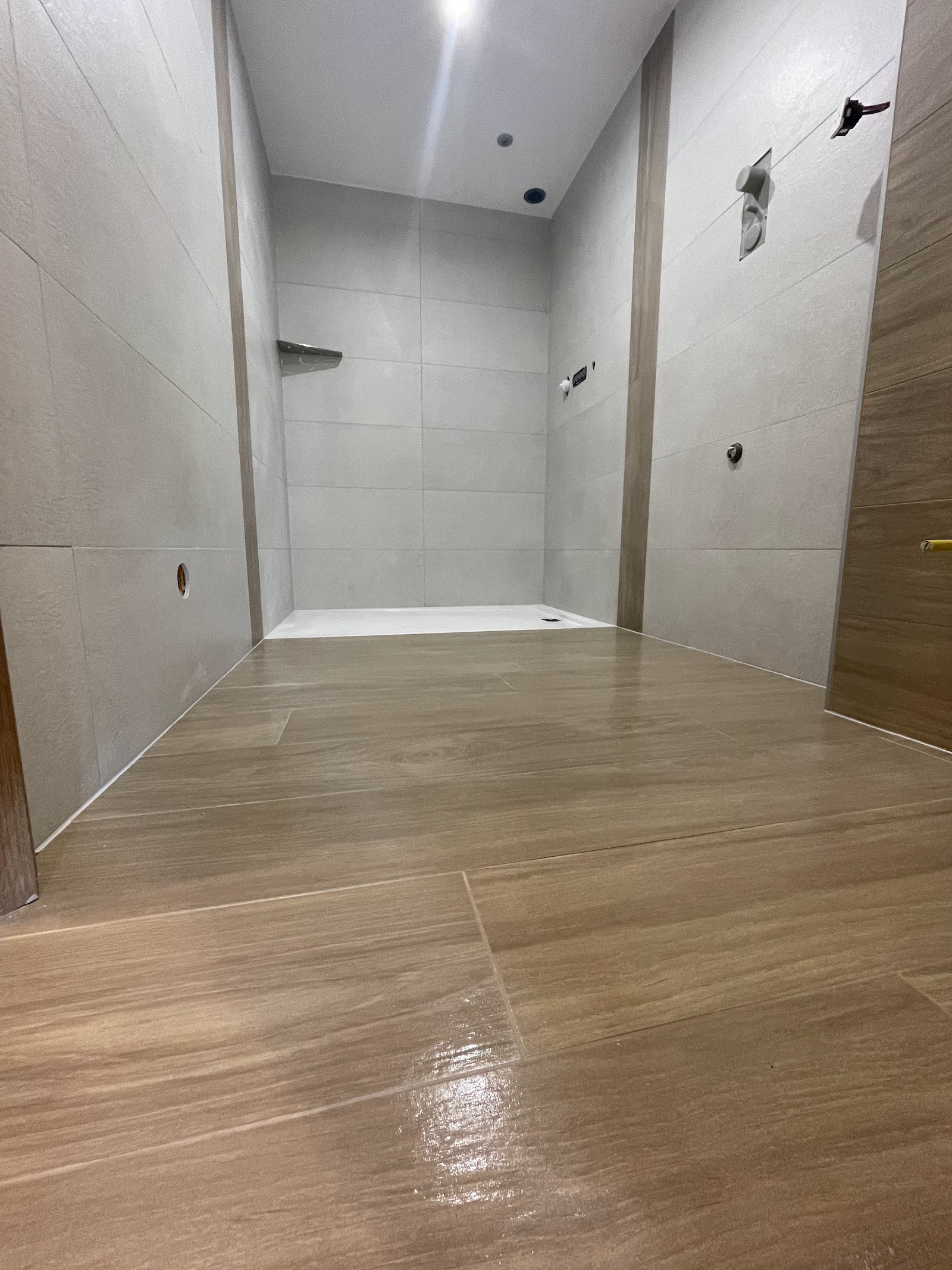 Douche à l'italienne spacieuse avec revêtement imitation bois.